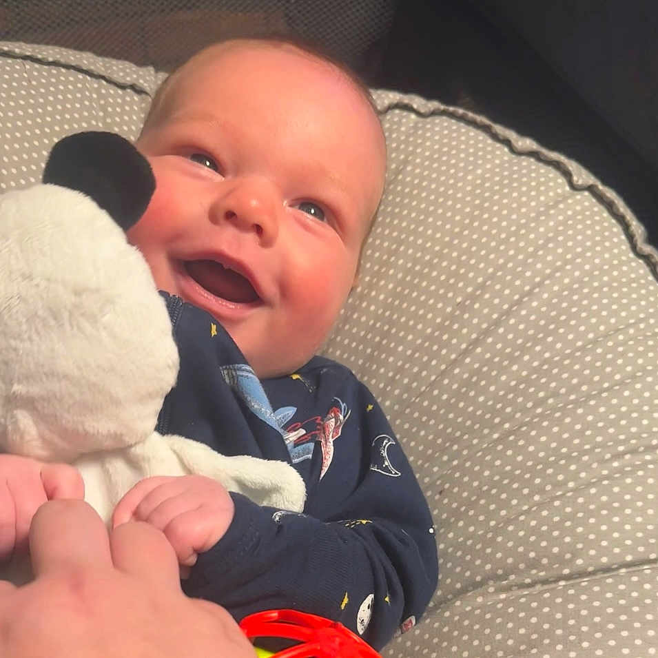 Waylon is registered to the contest to win money with this photo: baby, babylaughing, bed, bodypart, clothing, coat, couch, crib, cushion, face, finger, furniture, hand, happy, head, homedecor, infantbed, jacket, laughing, newborn