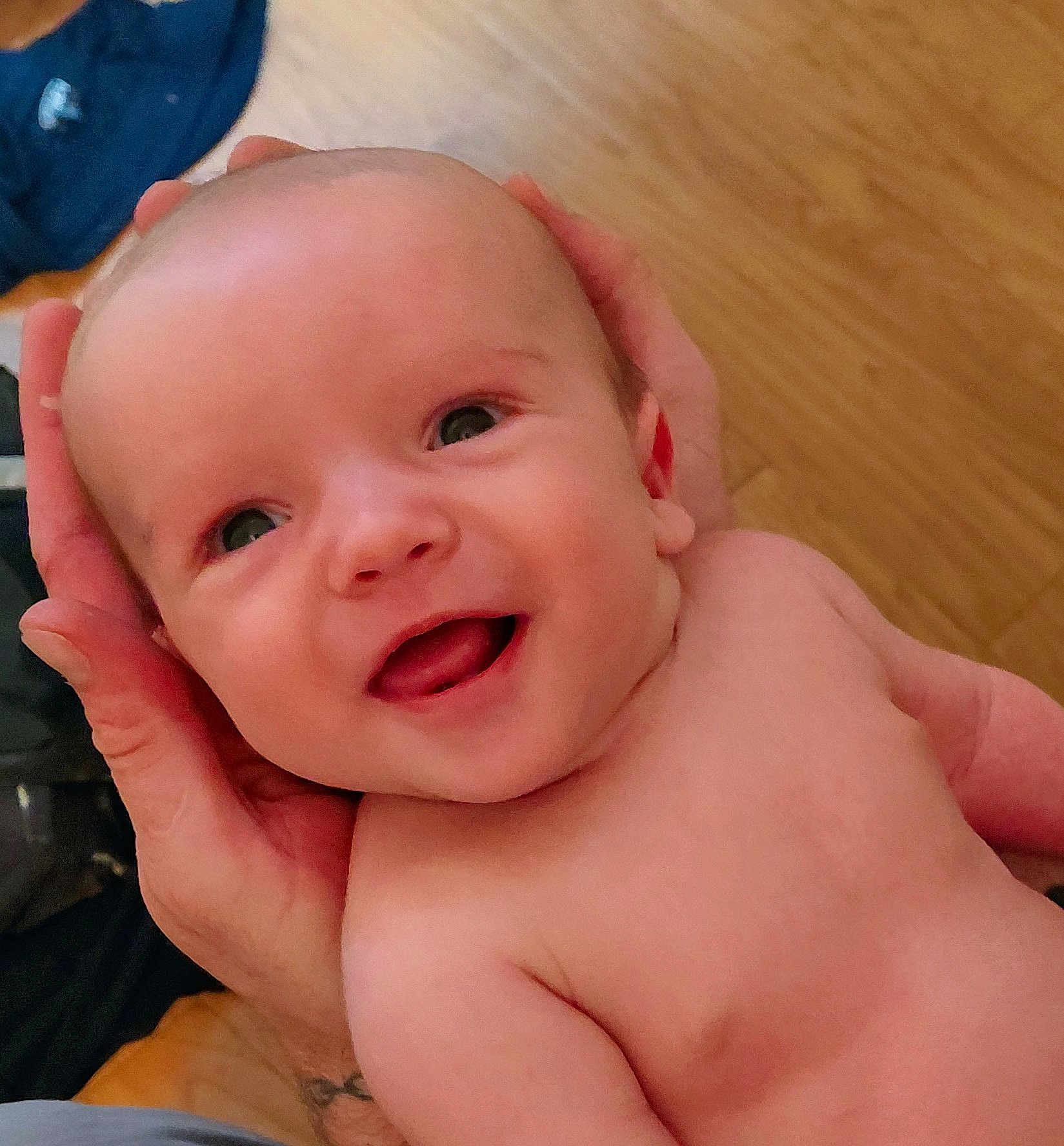 Jax is registered to the contest to win money with this photo: baby, smiling, happy, face, head, hands, skin, child, infant, portrait, bare_chest, person, cute, newborn, indoor, floor, wooden_floor, closeup, expression, joy
