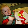 Alfie joined the competition — help win amazing prizes! toddler, child, painting, brush, art, smile, red_paint, yellow_paint, paper, table, apron, curly_hair, indoor, happy, art_activity, messy, creative, young_child, play, expression