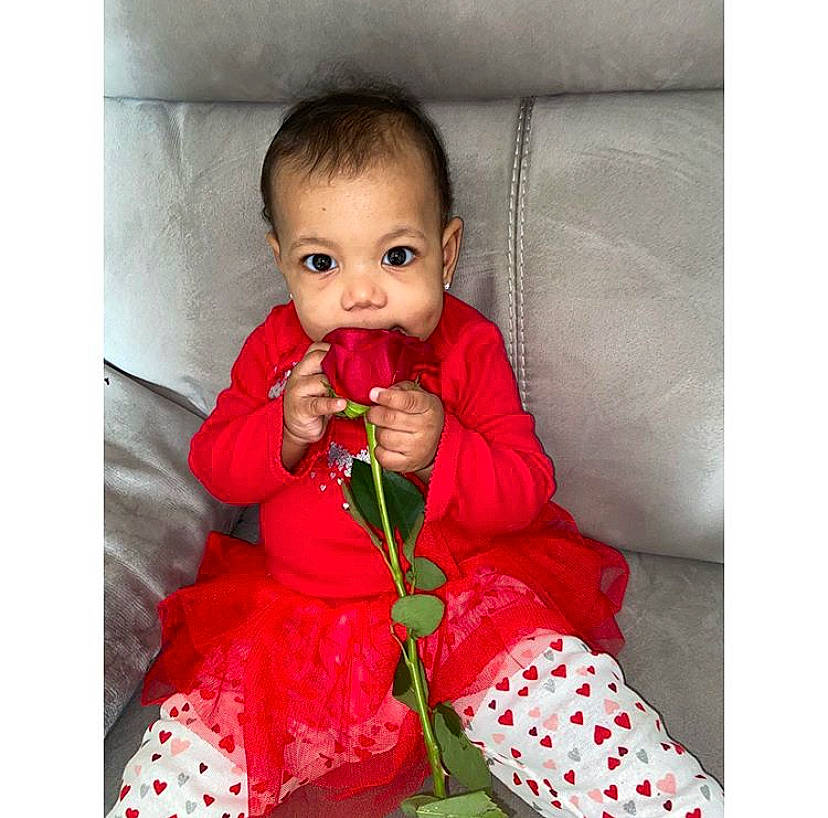 Teigan is registered to the contest to win money with this photo: baby, child, flower, happy, lip, mouth, outerwear, person, photography, plant, play, product, red, sitting, smile, toddler