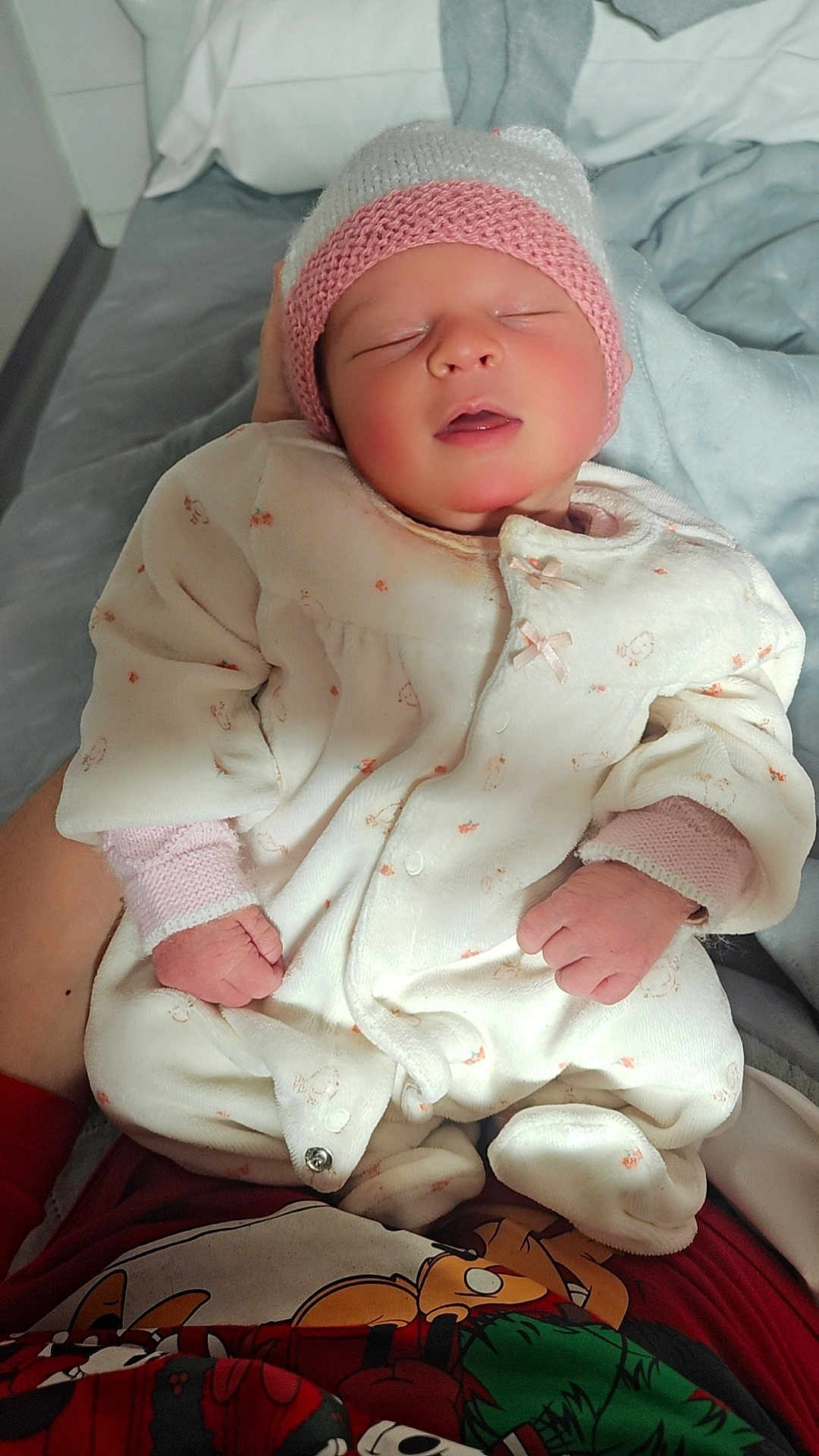 Lénna a rejoint le concours — aidez-le/la à gagner de superbes lots ! newborn, baby, sleeping, knit_hat, onesie, infant, hands, person, bed, blanket, cozy, cute, indoor, toddler, clothing, soft_lighting, cartoon_shirt, rest, peaceful, portrait