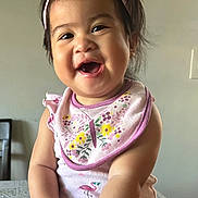 Gabriela joined the competition — help win amazing prizes! baby, child, smiling, laughing, headband, pink, bib, floral, sitting, table, indoor, cute, happy, person, infant, apparel, hands, face, skin, cheerful