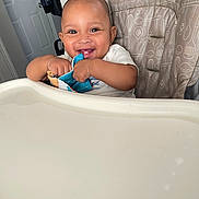 Malachi joined the competition — help win amazing prizes! baby, high_chair, smiling, happy, infant, toy, fabric, indoor, child, face, person, cushion, pattern, door, home, furniture, seat, cute, young, cheerful