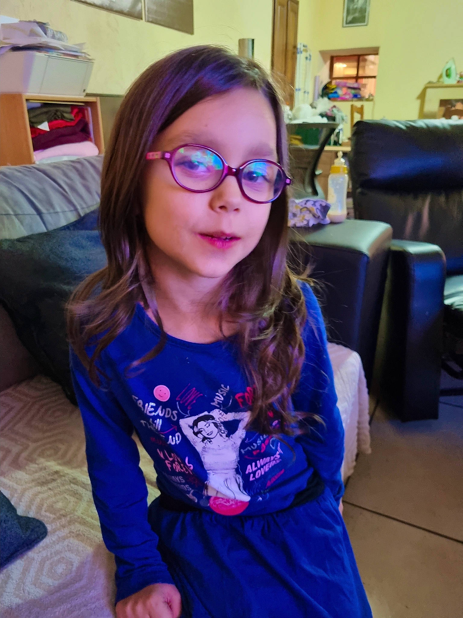 Clara participe au concours pour gagner de l'argent avec cette photo : blond, brown_hair, cool, couch, electric_blue, event, eyewear, fashion_accessory, finger, fun, glasses, happy, iris, long_hair, person, purple, sitting, sleeve, t_shirt, toddler
