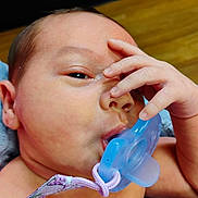 John is registered to the contest to win money with this photo: baby, pacifier, hand, face, skin, infant, closeup, mouth, fingers, expression, child, newborn, cute, portrait, indoors, person, skin_texture, sleepy, resting, soft
