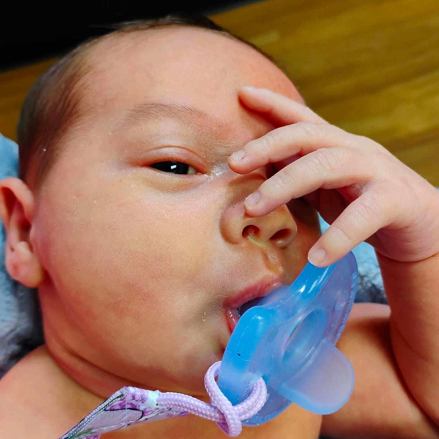 John is registered to the contest to win money with this photo: baby, pacifier, hand, face, skin, infant, closeup, mouth, fingers, expression, child, newborn, cute, portrait, indoors, person, skin_texture, sleepy, resting, soft
