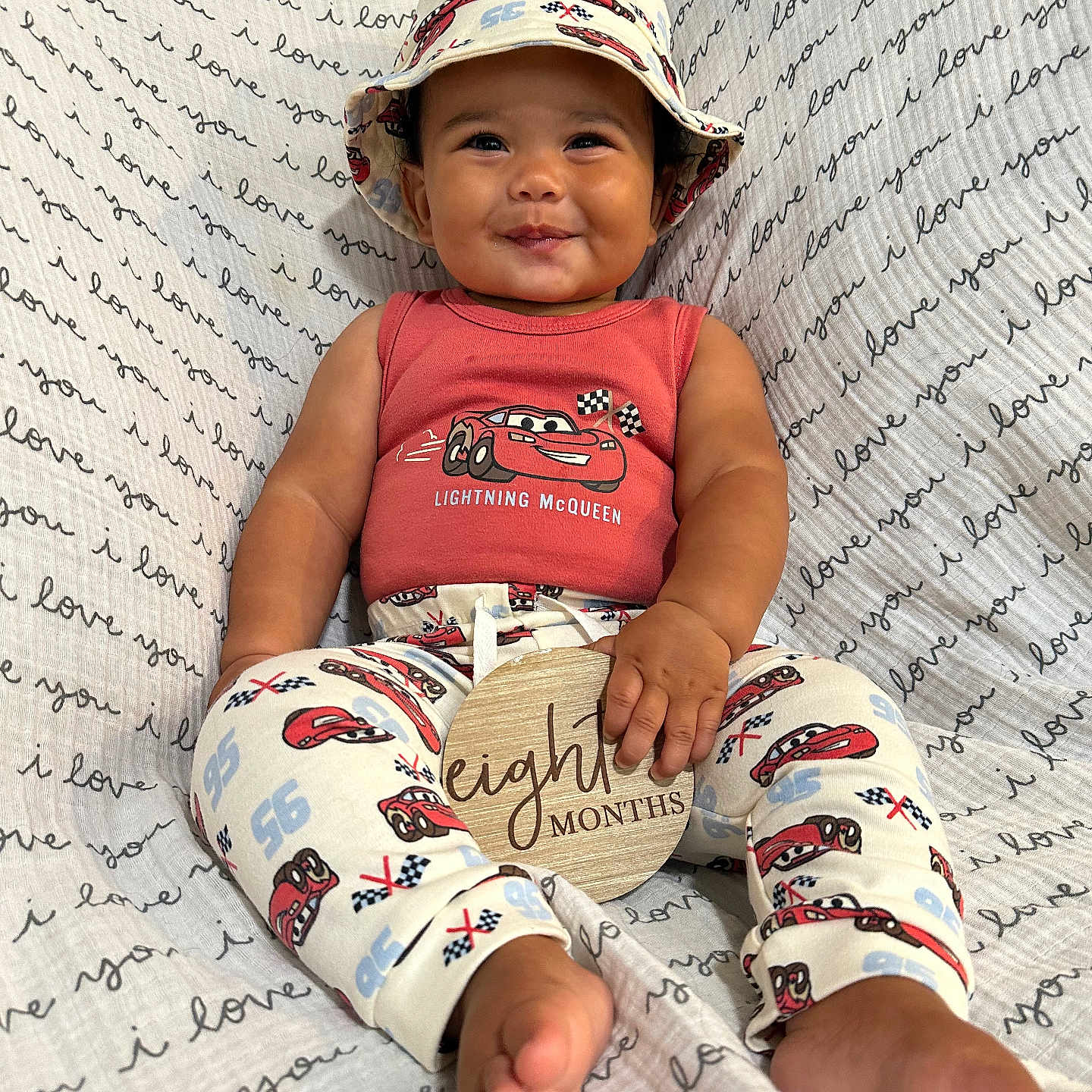 Davide joined the competition — help win amazing prizes! baby, blanket, child, clothing, cozy, cute, feet, happy, hat, indoor, infant, pants, pattern, person, portrait, shirt, sign, sitting, smile, text