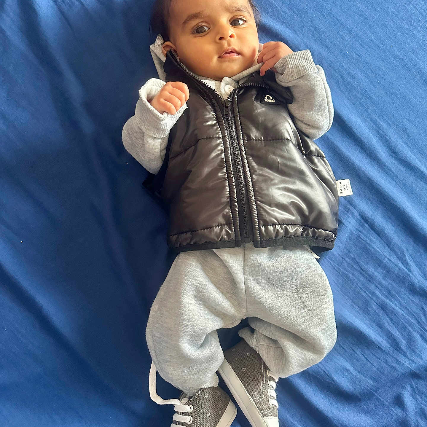 Dilawar joined the competition — help win amazing prizes! baby, blue_bedspread, casual_wear, child, clothing, cozy, cute, expression, face, footwear, hands, indoor, infant, lying_down, person, portrait, sneakers, sweatpants, vest, young_child