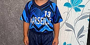 Yanis participe au concours pour gagner de l'argent avec cette photo : child, boy, smiling, sportswear, jersey, shorts, sneakers, blue, standing, indoor, wallpaper, floral_pattern, flooring, happy, portrait, casual, person, background, home, young