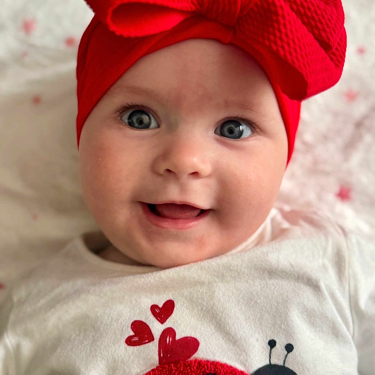 Athénaïs a rejoint le concours — aidez-le/la à gagner de superbes lots ! baby, child, smiling, face, headband, red_bow, blue_eyes, white_shirt, ladybug, hearts, cute, portrait, closeup, infant, happy, indoors, apparel, clothing, person, adorable