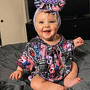 Saylor joined the competition — help win amazing prizes! baby, child, smiling, headband, blue_eyes, colorful_clothing, patterned_outfit, indoor, bed, blanket, happy, person, cute, sitting, infant, portrait, clothing, headwear, cheerful, young
