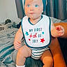 adult_arm, baby, bed, bib, blanket, celebration, child, clothing, curious, curtains, cute, headband, holiday, indoor, person, portrait, sitting, striped_onesie, white_shoes, window