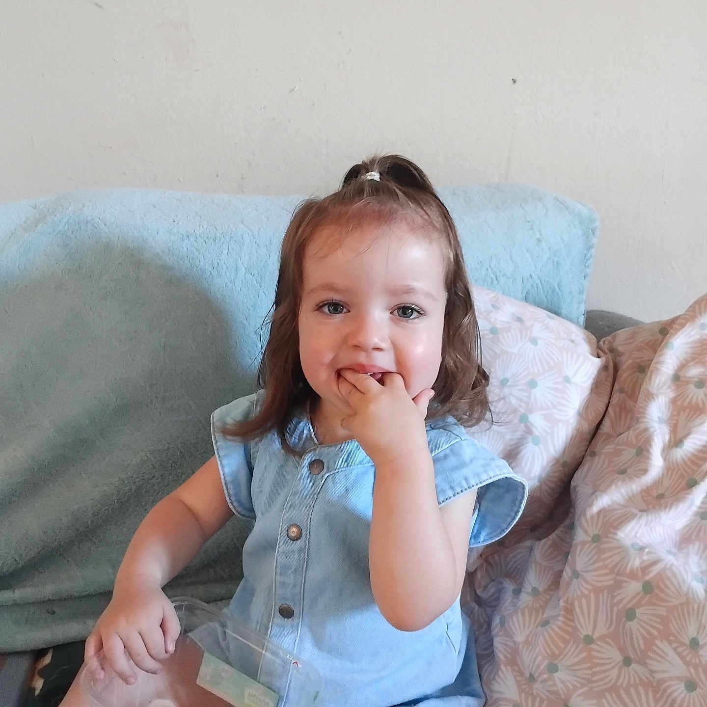 Alma a rejoint le concours — aidez-le/la à gagner de superbes lots ! blue_outfit, casual_clothing, child, couch, fingers_in_mouth, girl, hair_tie, happy, home, indoor, light_skin, person, pillows, plastic_container, playful, relaxed, sitting, smiling, toddler, toys