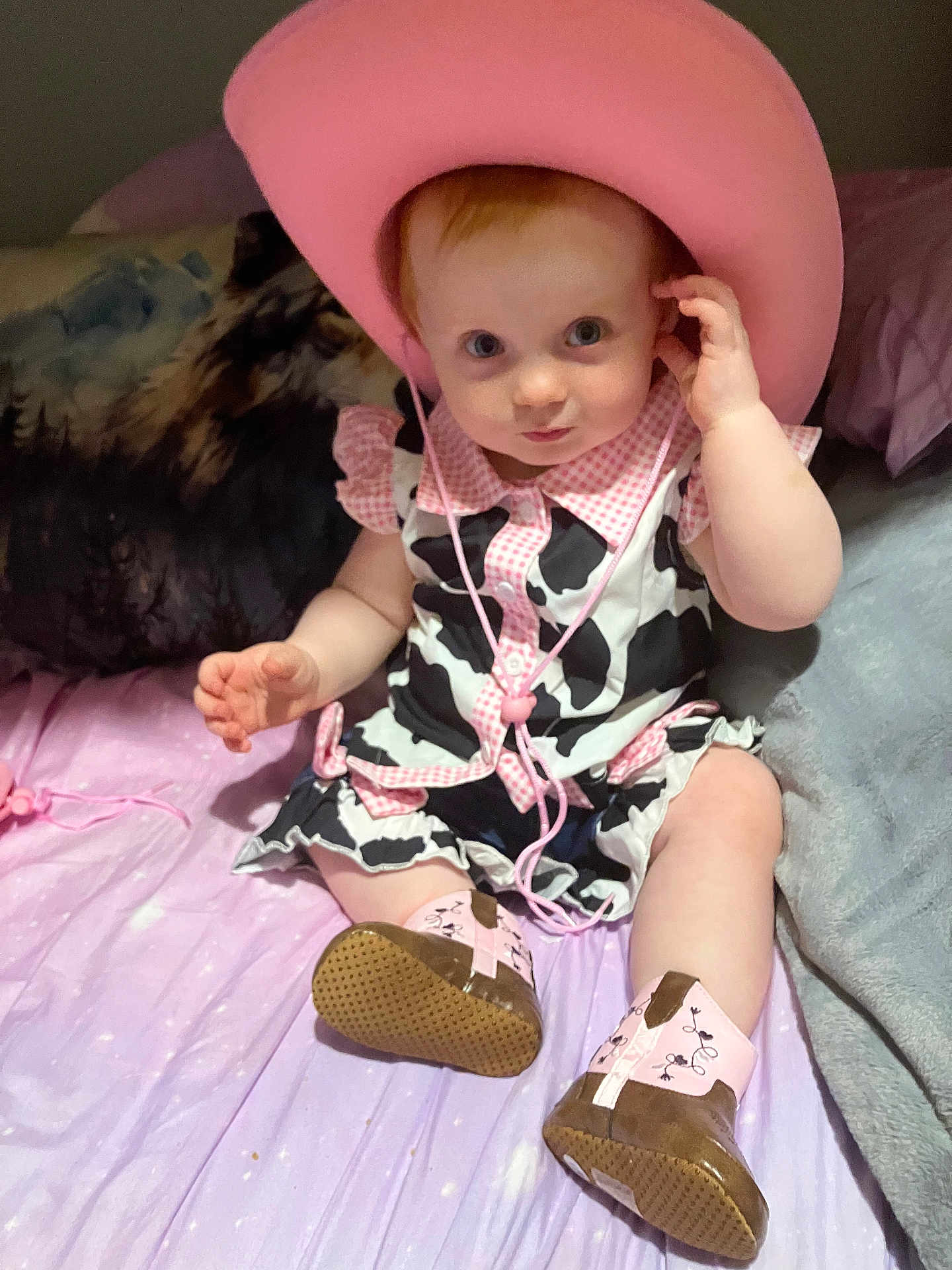 Harley joined the competition — help win amazing prizes! baby, child, cowboy_hat, pink_hat, cow_print, boots, bed, blanket, curious, cute, infant, clothing, portrait, indoor, person, sitting, young_child, footwear, cute_expression, playful