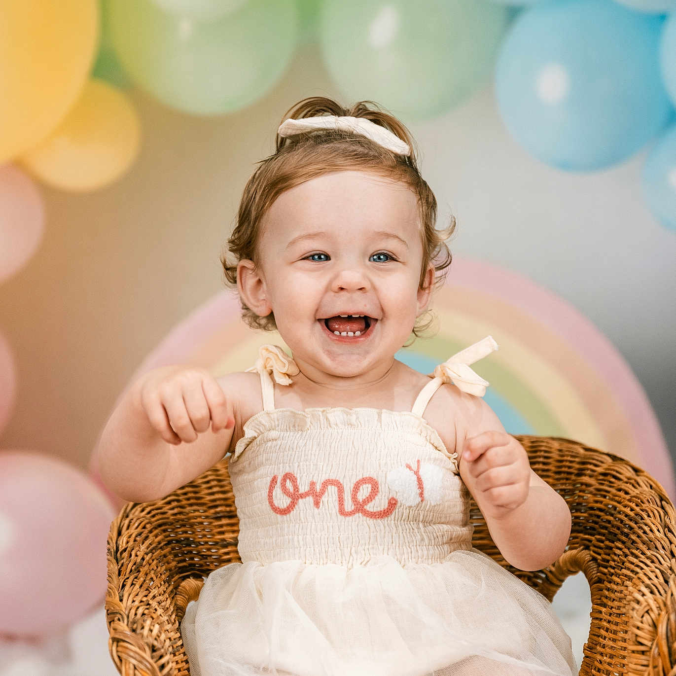 Hadleigh joined the competition — help win amazing prizes! balloons, birthday, blue_eyes, celebration, child, curly_hair, cute, decorations, dress, festive, happy, indoor, one_year_old, party, pastel_colors, portrait, rainbow, smiling, toddler, wicker_chair