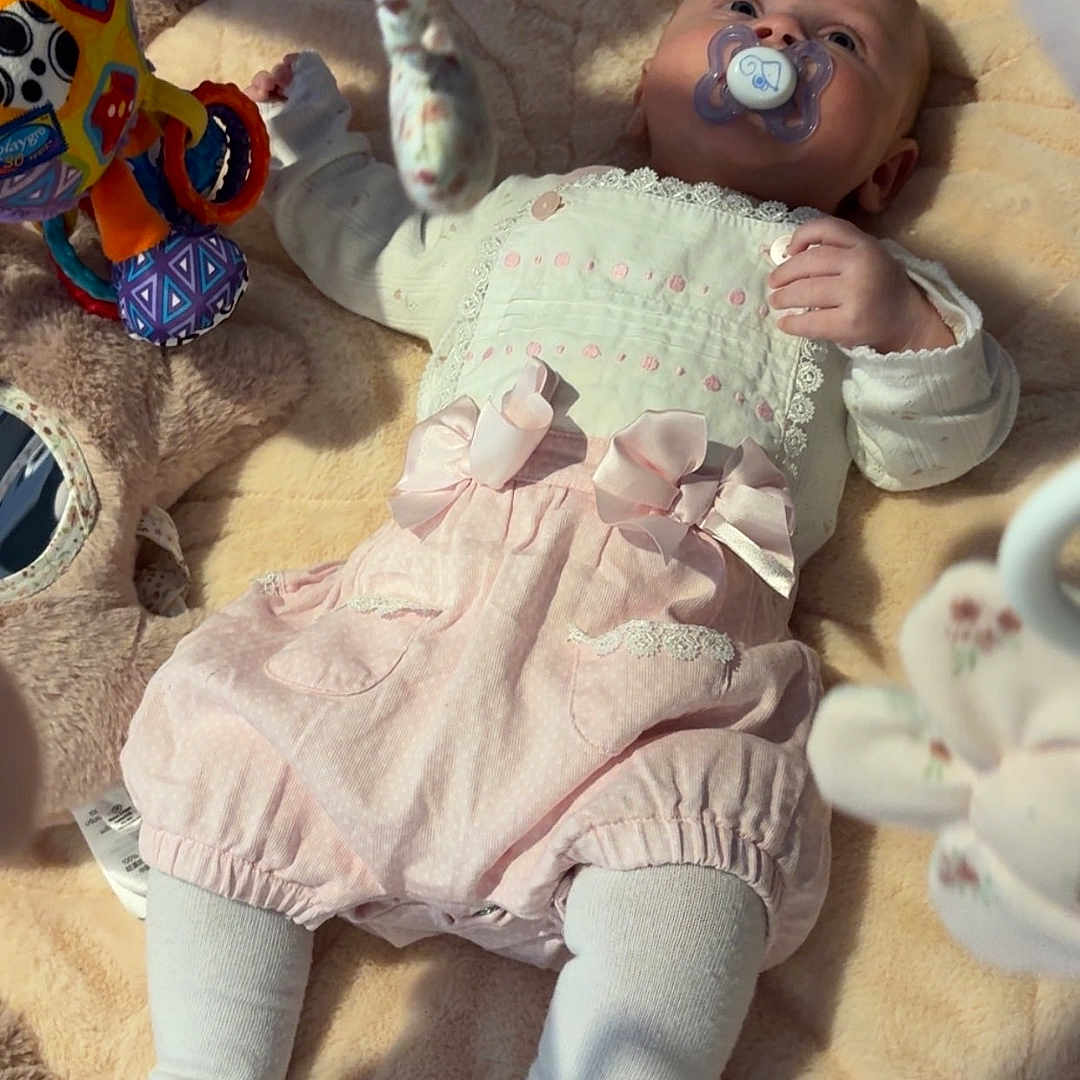 Lilly-Joan is registered to the contest to win money with this photo: baby, blanket, child, clothing, comfort, cute, face, indoor, infant, lying_down, newborn, pacifier, pink, play_area, plush, portrait, soft_toy, tights, toy, white