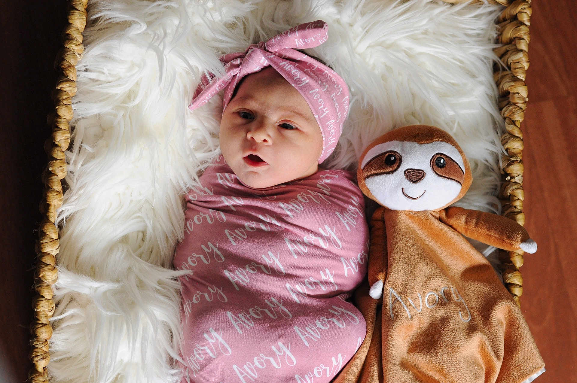 Avory joined the competition — help win amazing prizes! baby, swaddle, headband, pink, blanket, plush_toy, sloth, basket, fluffy, cushion, infant, cute, cozy, portrait, child, soft_toy, wooden_floor, lying_down, wrapped, adorable