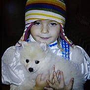 Simba is registered to the contest to win money with this photo: animal, blue_outfit, child, cozy, cute, dog, face, fluffy, hands, hat, holding, indoor, pet, portrait, puppy, smile, striped_hat, warm_clothing, white_puppy, young