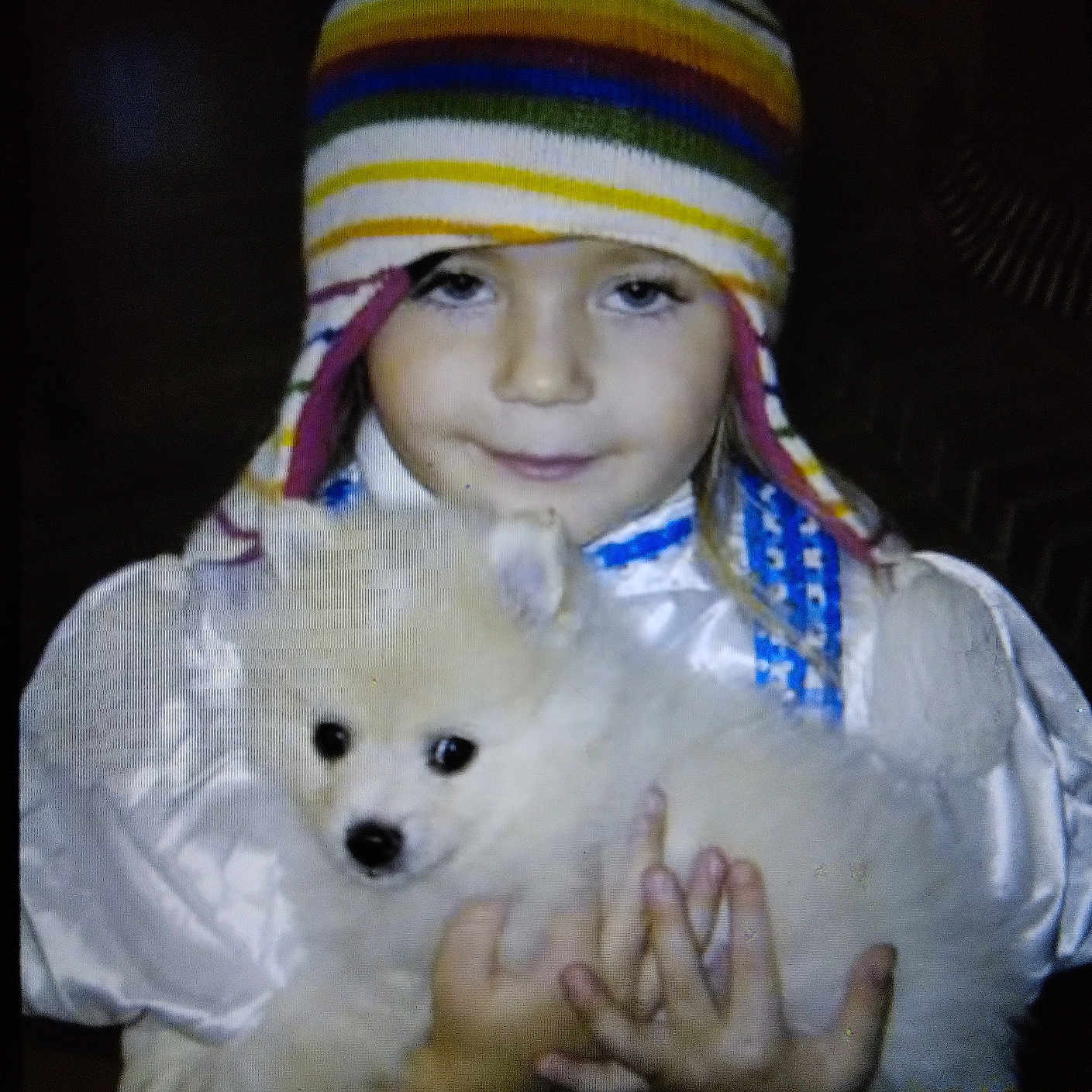 Simba is registered to the contest to win money with this photo: animal, blue_outfit, child, cozy, cute, dog, face, fluffy, hands, hat, holding, indoor, pet, portrait, puppy, smile, striped_hat, warm_clothing, white_puppy, young