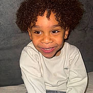 Kingsley participe au concours pour gagner de l'argent avec cette photo : child, smiling, curly_hair, sitting, white_sweatshirt, gray_pants, portrait, happy, face, young, indoors, casual_clothing, curly_afro, cute, person, joy, comfort, closeup, childhood, warmth