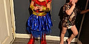 Elizabeth is registered to the contest to win money with this photo: child, children, indoor, costume, wonder_woman, dress, curly_hair, smile, boy, girl, carpet, wall, door, barefoot, playful, cute, person, standing, diaper, casual_clothing