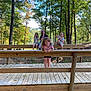 child, children, outdoor, wooden_bridge, trees, nature, playful, smiling, sunny_day, forest, snack, casual_clothing, wood, greenery, happy, playground, summer, friends, fun, leisure