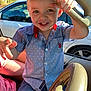child, boy, smiling, blue_shirt, car_interior, car_handle, sunlight, window, white_car, short_hair, happy, jeans, seat, hand, face, playful, portrait, daylight, vehicle, casual_clothing