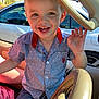 child, toddler, smiling, waving, blue_shirt, car_interior, car_seat, sunlight, happy, portrait, casual_clothing, short_hair, seatbelt, vehicle, window, daylight, outside, parking_lot, person, closeup