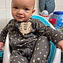 baby, child, infant, onesie, seat, smile, face, blue_oven_mitt, kitchen, container, counter, tile_wall, cute, cozy, patterned_clothing, sitting, indoor, home, person, young