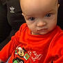 Leonardo is registered to the contest to win money with this photo: baby, child, person, sweater, red_clothing, mickey_mouse, blue_pants, indoor, portrait, face, eyes, head, expression, clothing, seated, adult, adidas, casual, cozy, holiday