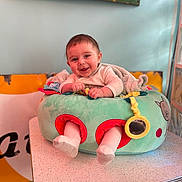 Mayron a rejoint le concours — aidez-le/la à gagner de superbes lots ! baby, background, child, clothing, colorful, comfort, cushion, cute, face, feet, happy, indoor, infant, legs, person, playful, smiling, soft, table, toy