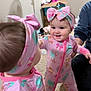 baby, child, mirror, reflection, pink, headband, pajamas, smiling, indoor, carpet, person, face, hand, toy, home, furniture, adult, support, cute, happy