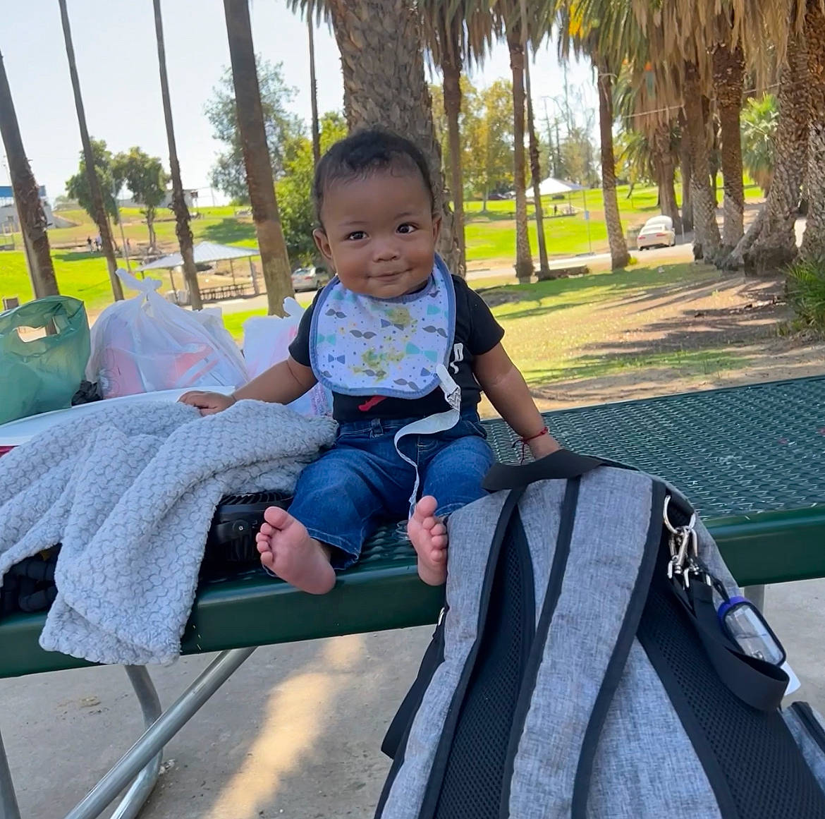Matteo is registered to the contest to win money with this photo: baby_toddler_clothing, comfort, electric_blue, fun, grass, happy, lap, leisure, mammal, outdoor_furniture, palm_tree, person, plant, public_space, recreation, sitting, smile, tints_and_shades, toddler, travel