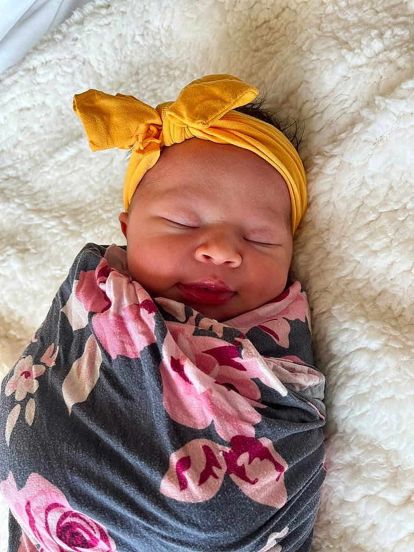 Gianna joined the competition — help win amazing prizes! baby, blanket, bow, child, cozy, cute, floral, headband, indoors, infant, newborn, peaceful, portrait, resting, sleeping, soft, texture, white, wrapped, yellow