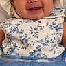 baby, child, infant, smiling, portrait, bonnet, dress, floral_pattern, blue_clothing, sitting, indoors, happy, face, eyes, mouth, fashion, baby_clothing, headwear, close_up, photography