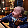 Saad joined the competition — help win amazing prizes! baby, child, high_chair, jacket, smile, indoor, wood, furniture, lighting, modern, decor, table, face, person, cute, seated, warm_lighting, happy, cozy, infant