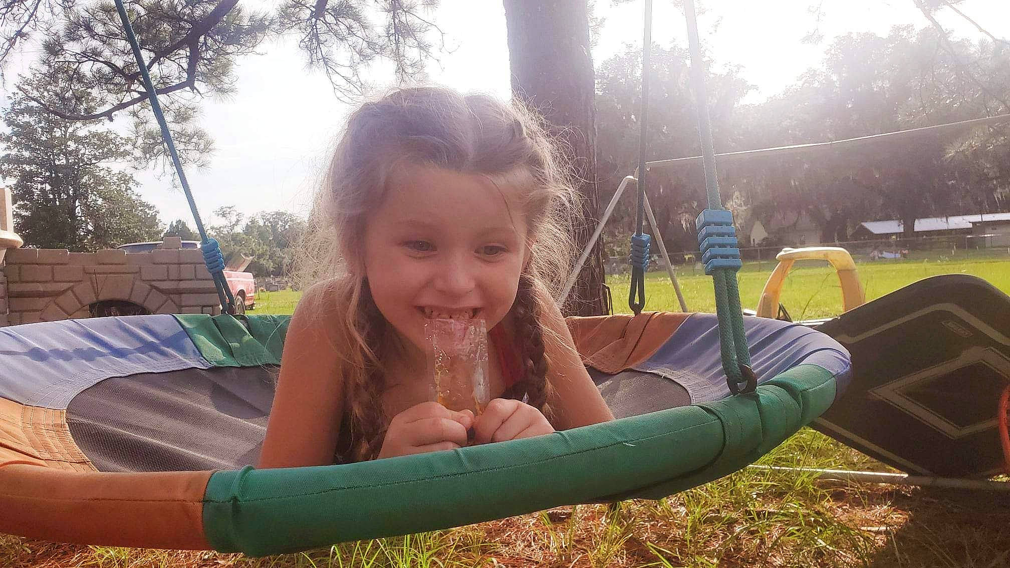Addilynn joined the competition — help win amazing prizes! child, chute, city, fun, grass, happy, joy, laugh, leisure, outdoor_play_equipment, people_in_nature, person, plant, play, playground, recreation, shade, sitting, sky, smile