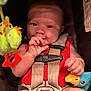 baby, child, car_seat, red_clothing, plush_toy, toy, infant, face, hand, seatbelt, cute, sitting, indoors, smiling, doll, colorful, portrait, childhood, happy, close_up