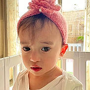 Elise participe au concours pour gagner de l'argent avec cette photo : toddler, child, face, portrait, pink_headband, knitted_headband, earring, white_shirt, playpen, crib, curtain, window, indoor, natural_light, close_up, big_eyes, sad_expression, hair, skin, fashion_accessory