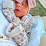 newborn, baby, sleeping, infant, portrait, pink_hat, mittens, floral_clothing, blanket, swaddled, peaceful, eyes_closed, outdoor, held, adult, soft_blanket, baby_clothing, cozy, pavement, grass
