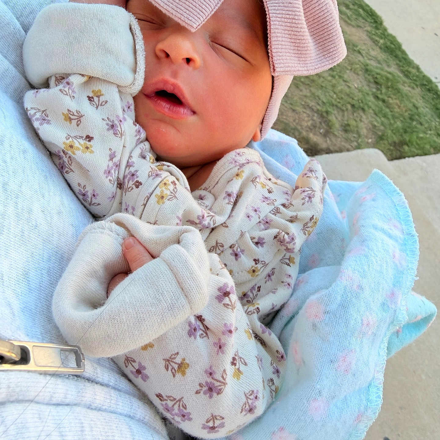 Paulina joined the competition — help win amazing prizes! newborn, baby, sleeping, infant, portrait, pink_hat, mittens, floral_clothing, blanket, swaddled, peaceful, eyes_closed, outdoor, held, adult, soft_blanket, baby_clothing, cozy, pavement, grass