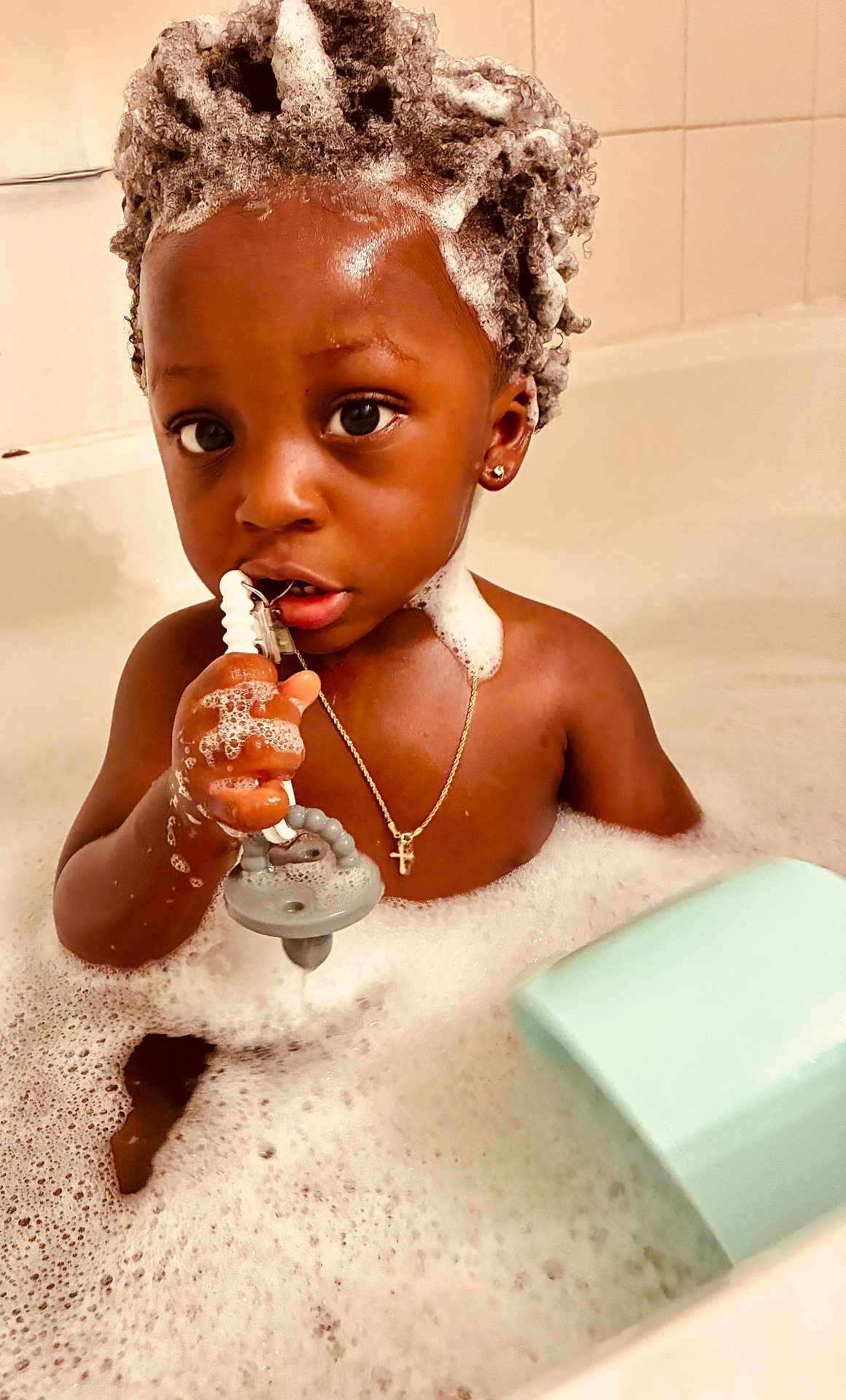 Kross is registered to the contest to win money with this photo: toddler, child, bath, bubbles, soap, bathroom, toy, water, skin, earring, necklace, chain, cross, foam, head, face, hand, expression, indoor, cute