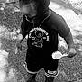 toddler, child, outdoor, hairbrush, black_and_white, tshirt, shorts, shoes, side_view, standing, shadow, sunlight, pavement, casual_clothing, necklace, curly_hair, person, young_child, summer, playful