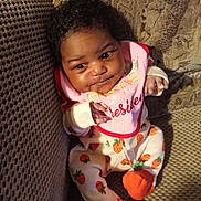 Knoréal joined the competition — help win amazing prizes! baby, bib, child, clothing, couch, curly_hair, cute, fabric, face, footwear, hand, indoor, infant, orange, patterned_clothing, portrait, seated, smiling, strawberry, textile