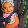 baby, child, car_seat, graco, flower_headband, smile, seatbelt, infant, cute, sitting, clothing, pink, gray, hand, face, headwear, safety, toddler, indoors, happy