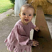 Capucine a rejoint le concours — aidez-le/la à gagner de superbes lots ! baby, bench, casual, child, concrete_floor, cute, daylight, girl, grass, greenery, happy, outdoor, pigtails, pink_dress, portrait, shoes, smiling, standing, wooden_bench, young_child