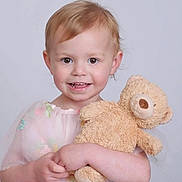Olivia is registered to the contest to win money with this photo: child, toddler, smile, teddy_bear, plush_toy, dress, sheer_fabric, embroidery, cute, portrait, happy, light_hair, baby, innocence, studio_photo, holding, soft_toy, young_child, childhood, playful