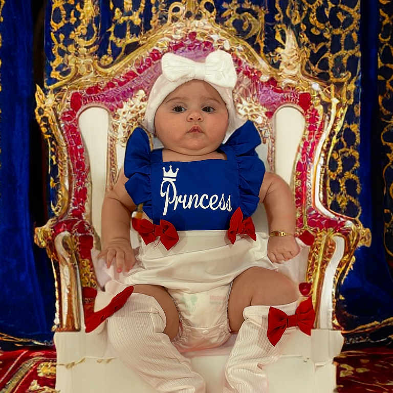 Kylie is registered to the contest to win money with this photo: adorable, baby, blue_outfit, carpet, child, cute, diaper, gold_decoration, indoor, knee_high_socks, person, portrait, princess, red_bows, royalty, serious_expression, sitting, throne, velvet_curtains, white_bow