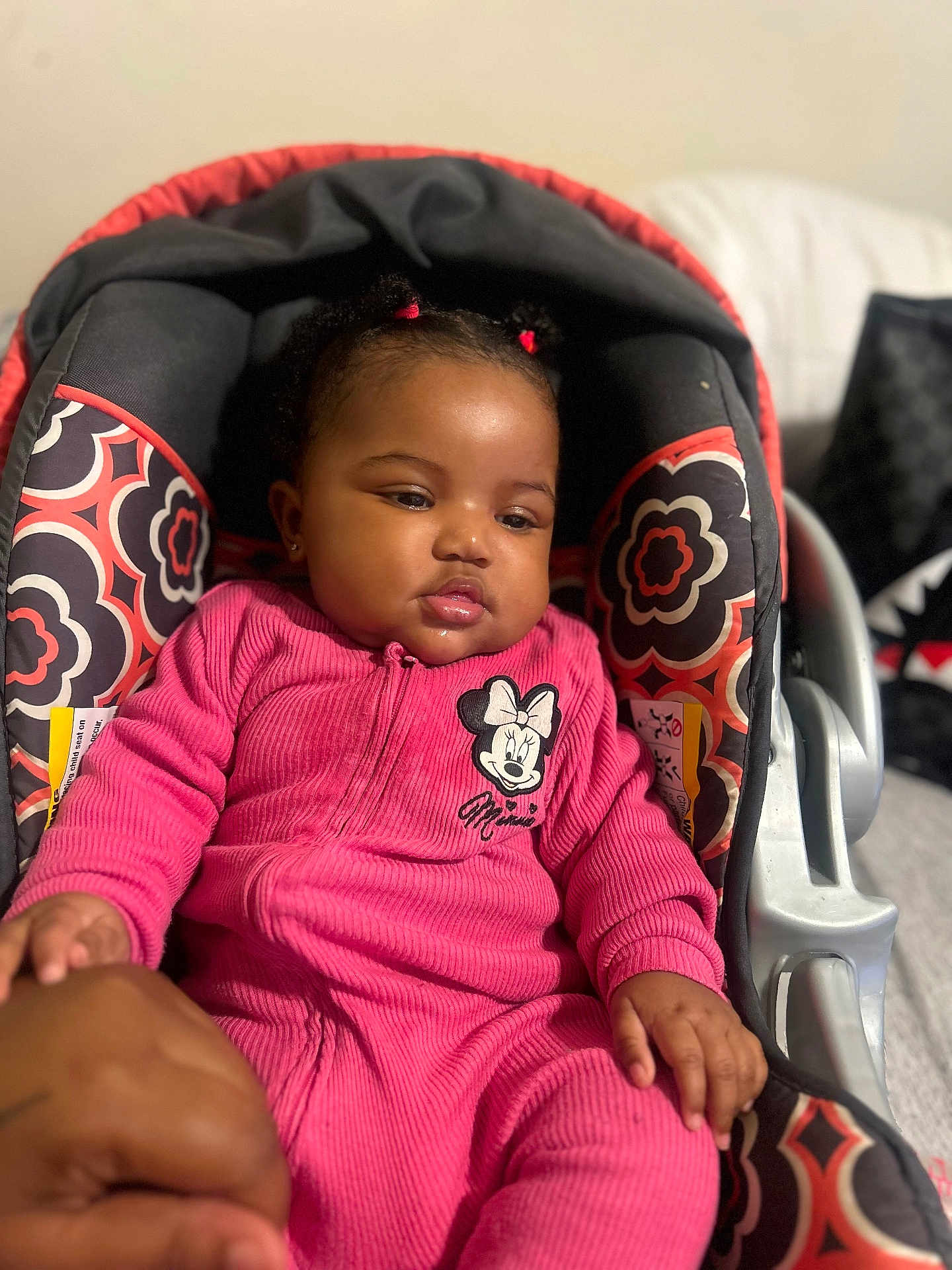 Serenity joined the competition — help win amazing prizes! baby, child, infant, car_seat, pink_clothing, minnie_mouse, onesie, patterned_fabric, hand_holding, pigtails, indoors, portrait, cute, toddler, seated, young_child, soft_lighting, close_up, person, face
