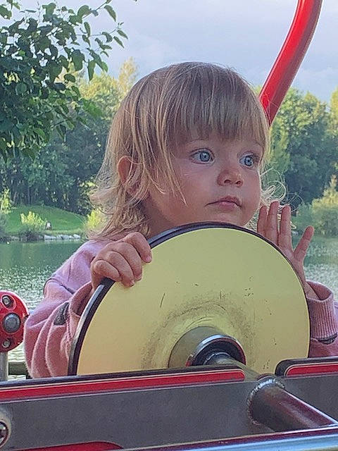 Sophia a rejoint le concours — aidez-le/la à gagner de superbes lots ! auto_part, automotive_wheel_system, boat, boats_and_boating_equipment_and_supplies, child, eye, fun, grass, hair, happy, leisure, motor_vehicle, person, plant, recreation, sky, steering_wheel, toddler, tree, watercraft